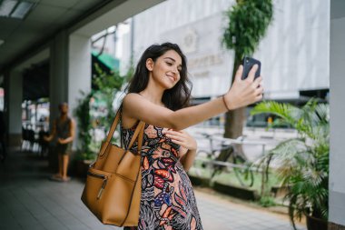 Genç, güzel ve zarif Punjabi Hint Asyalı kadın kendini bir selfie onun smartphone ile yoğun bir cadde üzerinde gün boyunca alır