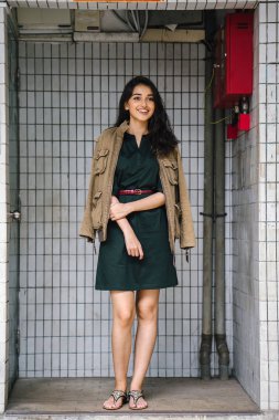 Hint Asyalı kadın Genç, uzun boylu, ince ve zarif bir portre için poz veriyor. O rahat ve şık rahat giysiler giyiyor ve bir adamın ceketi omuzları üzerinde bol dökümlü vardır. 