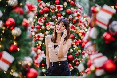 güzel orta yaşlı kadın mutlu onun smartphone üzerinde konuşuyor ve aynı derecede o durgunluk ortasında güzel gülümseyen gün boyunca Noel ağaçları dekore edilmiş olan