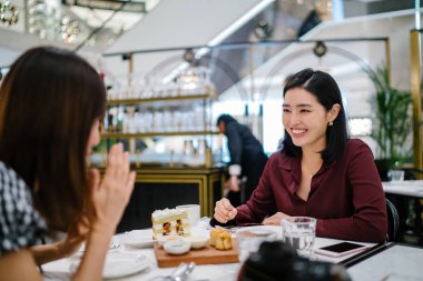 güzel ve zarif Kore Asya kadın çay ve kek ile onun en iyi arkadaşı bir kafede ile hafta sonu keyif alıyor.