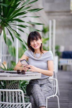 Çekici, kendine güvenen ve başarılı bir Çinli Asyalı kadının portresi. Akıllı telefonunu tutuyor. 