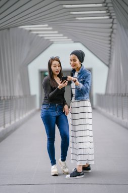 Gündüz vakti köprüde farklı etnik kökenlere sahip iki arkadaş. Biri Malezyalı Müslüman bir kadın, diğeri de Çinli bir Asyalı. İkisi de genç, enerjik ve çekici..