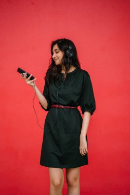 Bir güzel, Genç ve çekici Hint Asyalı kadın bir yeşil elbise ve kırmızı bir arka plan kırmızı kemer Studio portresi