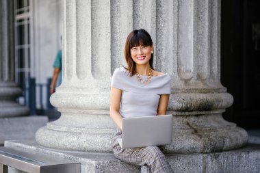 Modern dizüstü bilgisayar kullanarak çekici, kendine güvenen ve başarılı bir Çinli Asyalı kadının portresi