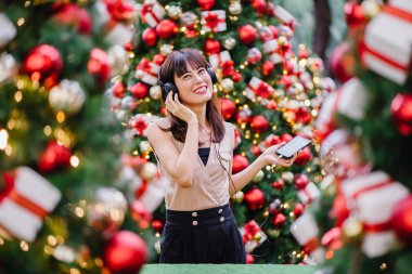 Gün boyunca birkaç süslü Noel ağaçları arasında duran zarif ve çekici bir orta yaşlı kadın portresi