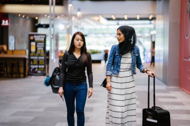 İki arkadaş, Orchard Road, Singapur, Asya 'da aydınlık bir yaz gününde mutlu bir şekilde yürüyüp konuşurlar. Biri Müslüman Malezyalı, diğeri Çinli bir kadın.. 