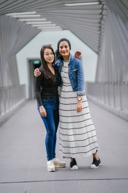 Gündüz vakti köprüde farklı etnik kökenlere sahip iki arkadaş. Biri Malezyalı Müslüman bir kadın, diğeri de Çinli bir Asyalı. İkisi de genç, enerjik ve çekici..