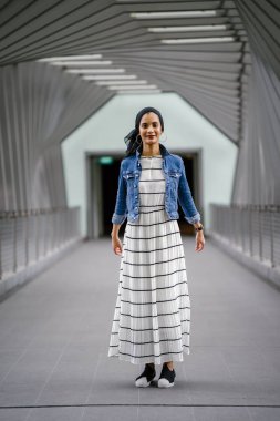 Gün boyunca güzel bir köprüde tek başına duran uzun boylu, genç, zarif ve çekici Malezyalı Müslüman bir kadının portresi..