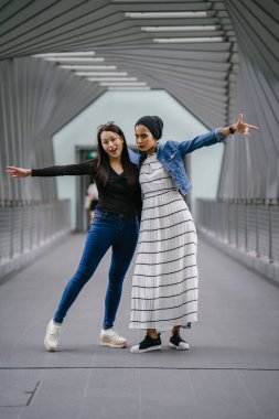 Gündüz vakti köprüde farklı etnik kökenlere sahip iki arkadaş. Biri Malezyalı Müslüman bir kadın, diğeri de Çinli bir Asyalı. İkisi de genç, enerjik ve çekici..