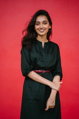 Stüdyo bir güzel, Genç ve çekici Hint Asyalı kadın kırmızı studio çerçevede bir portresi. O zarif bir basit yeşil elbise ve kırmızı kuşak giymiş ve gülüyor.