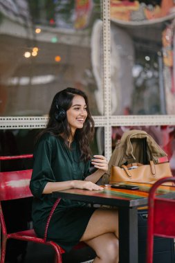 Genç Hintli Asyalı kadın o onun Smartphone-e doğru onun kulaklık streaming müzik hoşlanır