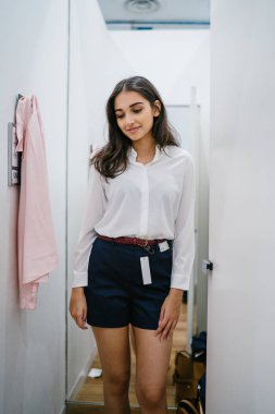 Trying dışarı giyim moda mağaza montaj odasında bir genç, uzun boylu, güzel ve zarif Hint Asyalı kadın portresi.