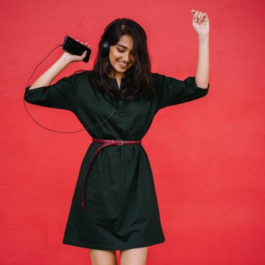 Bir güzel, Genç ve çekici Hint Asyalı kadın bir yeşil elbise ve kırmızı bir arka plan kırmızı kemer Studio portresi