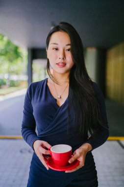 Modern bir altın özelliği duvara karşı şık ve zarif mavi elbise genç ve güzel Asyalı Çinli kadın Portresi. O bir fincan çay tutuyor ve kibirli ve aristokrat görünür. 