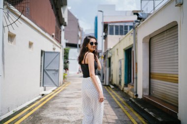 Genç, uzun boylu, ince ve zarif Hint Asyalı kadın rahat bir kıyafet içinde Asya bir sokakta bir sokakta aşağı gün boyunca yürür