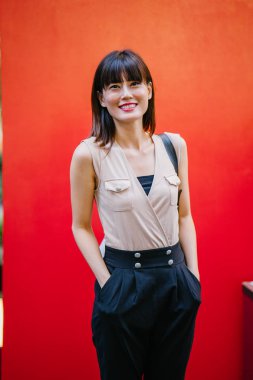 Bir çalışma hanım o pozlar ve onun baş shot kırmızı bir arka plan için gülümsüyor olarak stüdyo portresi