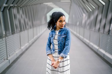 Gün boyunca güzel bir köprüde tek başına duran uzun boylu, genç, zarif ve çekici Malezyalı Müslüman bir kadının portresi..