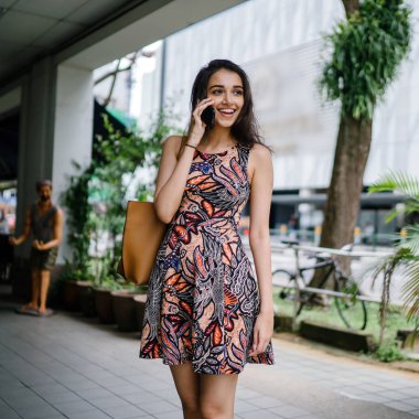 Ayakta ve gün boyunca onun smartphone bir şehirde Asya kentsel bir sokakta konuşurken Genç Hintli Asyalı kadın