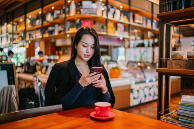 Bir açık havada açık havada oturan ve kırmızı bir çay seti çay sıcak bir fincan zevk genç, çekici, zarif ve güzel Asyalı kadın Portresi. 