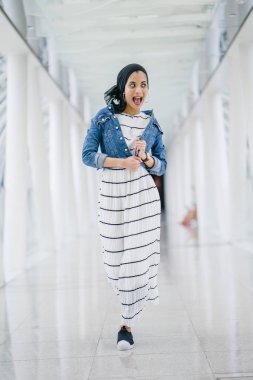 Genç, zarif ve çekici Malezyalı Müslüman kadın gün boyunca elbise ve kot ceket giyiyor..