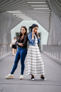Gündüz vakti köprüde farklı etnik kökenlere sahip iki arkadaş. Biri Malezyalı Müslüman bir kadın, diğeri de Çinli bir Asyalı. İkisi de genç, enerjik ve çekici..