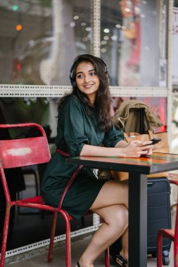 Genç Hintli Asyalı kadın o onun Smartphone-e doğru onun kulaklık streaming müzik hoşlanır