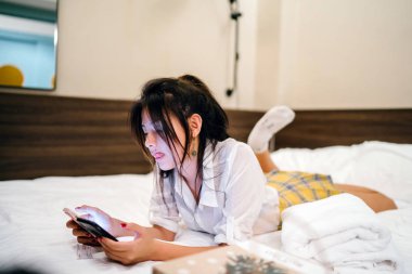 Genç Asyalı kız otel yatağında yatıyor. 