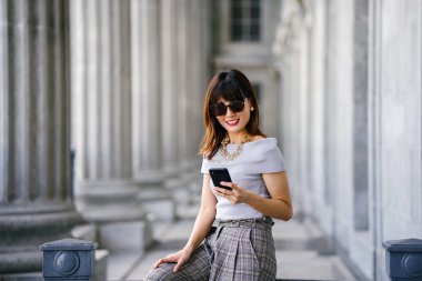 Çekici, kendine güvenen ve başarılı bir Çinli Asyalı kadının portresi. Akıllı telefonunu tutuyor. 