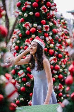 Genç, güzel ve mutlu bir Hint Asyalı kadın şenlikli Noel portresi bir hediye bir Noel ağacı önünde tutan gülümseyerek.