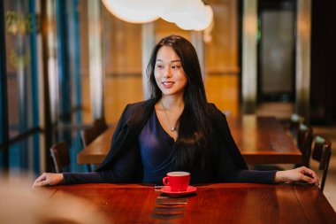 Bir açık havada açık havada oturan ve kırmızı bir çay seti çay sıcak bir fincan zevk genç, çekici, zarif ve güzel Asyalı kadın Portresi. 