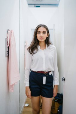Trying dışarı giyim moda mağaza montaj odasında bir genç, uzun boylu, güzel ve zarif Hint Asyalı kadın portresi.