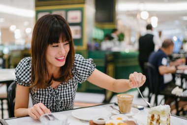 Bir Çinli Asyalı bayan bir restoranda iyi bir arkadaş ile yüksek çay sahiptir. O güzel, zarif ve o bir hafta sonu kek ve çay üzerinde arkadaşı ile animatedly konuşuyor gibi gülümsüyor.
