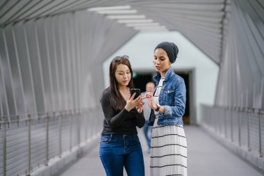 Gündüz vakti köprüde farklı etnik kökenlere sahip iki arkadaş. Biri Malezyalı Müslüman bir kadın, diğeri de Çinli bir Asyalı. İkisi de genç, enerjik ve çekici..