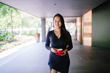 Modern bir altın özelliği duvara karşı şık ve zarif mavi elbise genç ve güzel Asyalı Çinli kadın Portresi. O bir fincan çay tutuyor ve kibirli ve aristokrat görünür. 