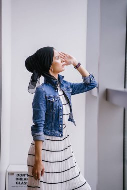 Genç, zarif ve çekici Malezyalı Müslüman kadın gün boyunca elbise ve kot ceket giyiyor..