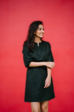 Stüdyo bir güzel, Genç ve çekici Hint Asyalı kadın kırmızı studio çerçevede bir portresi. O zarif bir basit yeşil elbise ve kırmızı kuşak giymiş ve gülüyor.