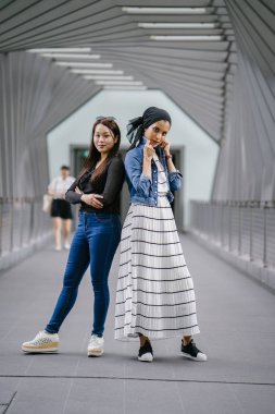 Gündüz vakti köprüde farklı etnik kökenlere sahip iki arkadaş. Biri Malezyalı Müslüman bir kadın, diğeri de Çinli bir Asyalı. İkisi de genç, enerjik ve çekici..