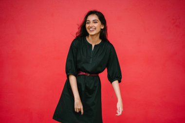 Stüdyo bir güzel, Genç ve çekici Hint Asyalı kadın kırmızı studio çerçevede bir portresi. O zarif bir basit yeşil elbise ve kırmızı kuşak giymiş ve gülüyor.