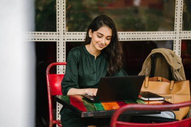 genç üniversite öğrencisi (Hint Asyalı kadın) eğitim ve gün boyunca dizüstü bilgisayar bir masa başında çalışma