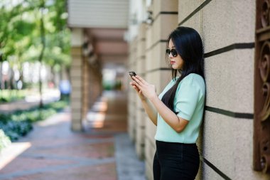 Akıllı telefon tutan genç ve güzel Asyalı bir Çinli kadının portresi.