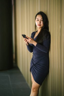 Akıllı telefon tutan genç ve güzel Asyalı bir Çinli kadının portresi.