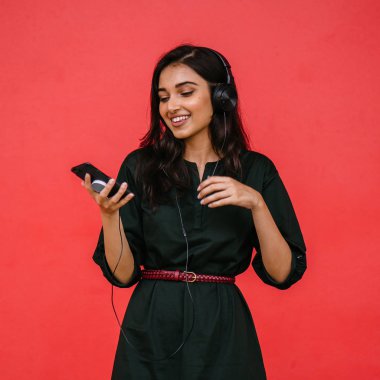 Bir güzel, Genç ve çekici Hint Asyalı kadın bir yeşil elbise ve kırmızı bir arka plan kırmızı kemer Studio portresi