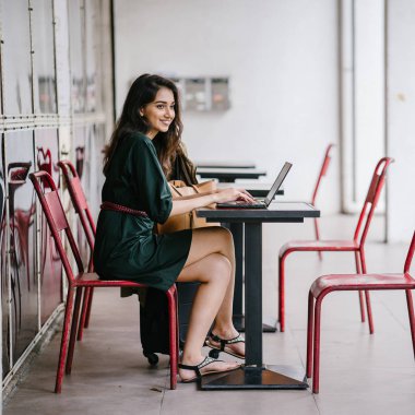 genç üniversite öğrencisi (Hint Asyalı kadın) eğitim ve gün boyunca dizüstü bilgisayar bir masa başında çalışma