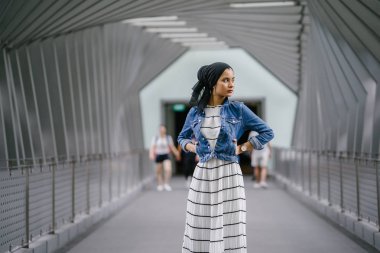 Genç, zarif ve çekici Malezyalı Müslüman kadın gün boyunca elbise ve kot ceket giyiyor..