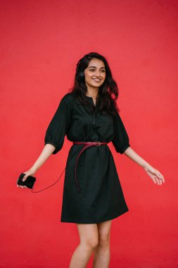 Bir güzel, Genç ve çekici Hint Asyalı kadın bir yeşil elbise ve kırmızı bir arka plan kırmızı kemer Studio portresi