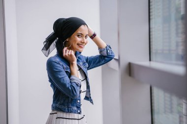 Genç, zarif ve çekici Malezyalı Müslüman kadın gün boyunca elbise ve kot ceket giyiyor..