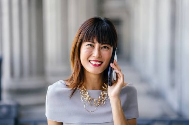 Çekici, kendine güvenen ve başarılı bir Çinli Asyalı kadının portresi. Akıllı telefonuyla konuşuyor. 