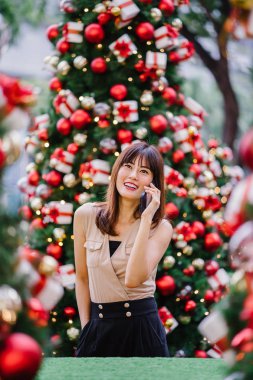 güzel orta yaşlı kadın mutlu onun smartphone üzerinde konuşuyor ve aynı derecede o durgunluk ortasında güzel gülümseyen gün boyunca Noel ağaçları dekore edilmiş olan