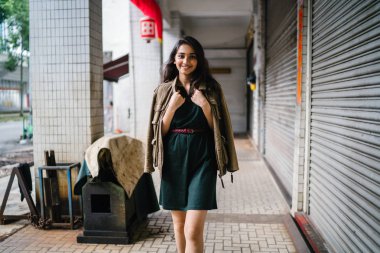 Hint Asyalı kadın Genç, uzun boylu, ince ve zarif bir portre için poz veriyor. O rahat ve şık rahat giysiler giyiyor ve bir adamın ceketi omuzları üzerinde bol dökümlü vardır. 