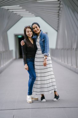 Gündüz vakti köprüde farklı etnik kökenlere sahip iki arkadaş. Biri Malezyalı Müslüman bir kadın, diğeri de Çinli bir Asyalı. İkisi de genç, enerjik ve çekici..